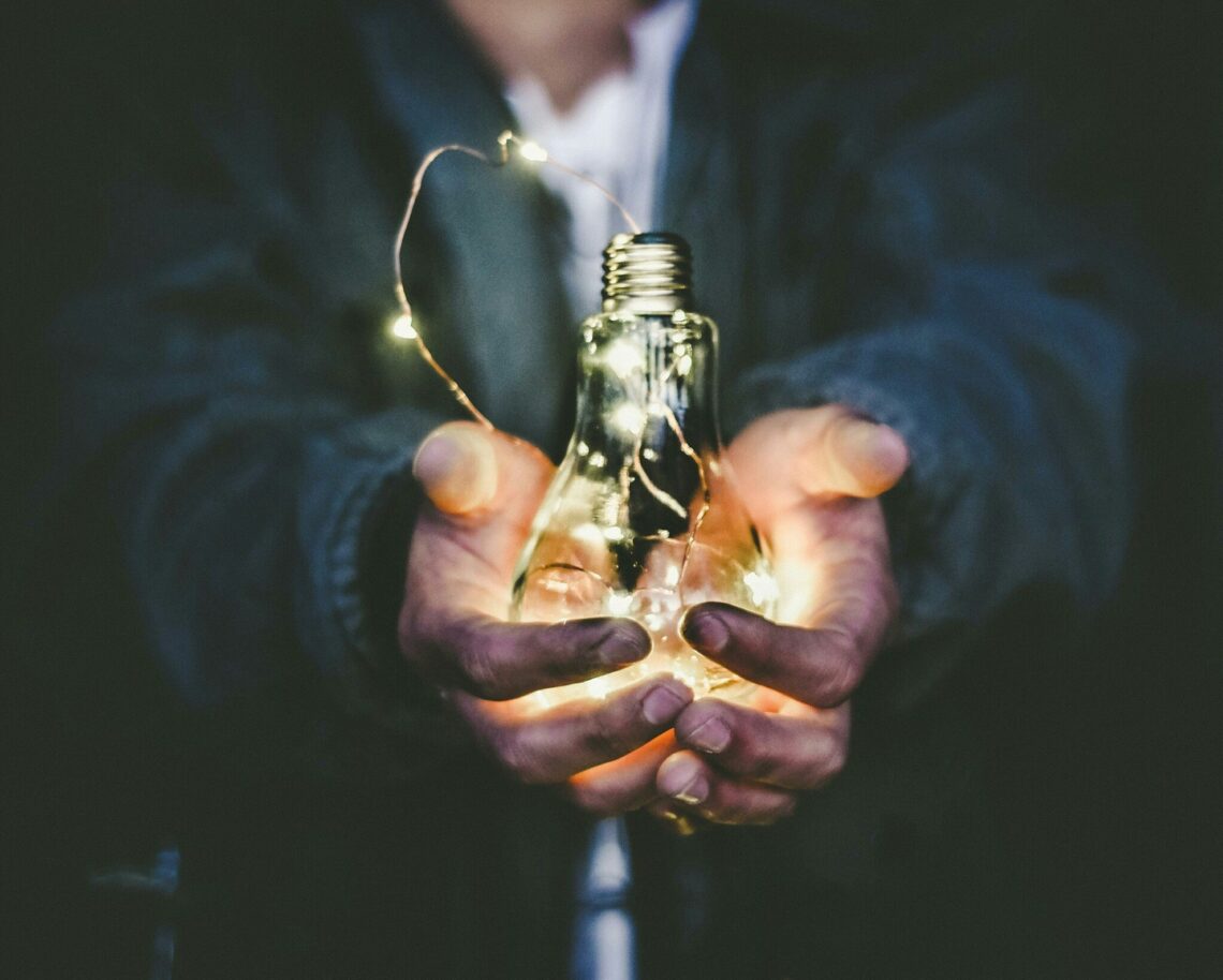 a person holding a light bulb with lights in their hands