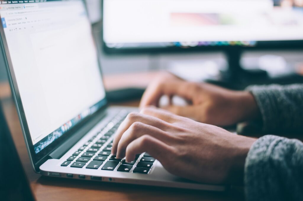 Close-up of hands typing on a laptop keyboard.