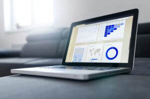 Laptop on desk displaying graphs and charts with analysis data.